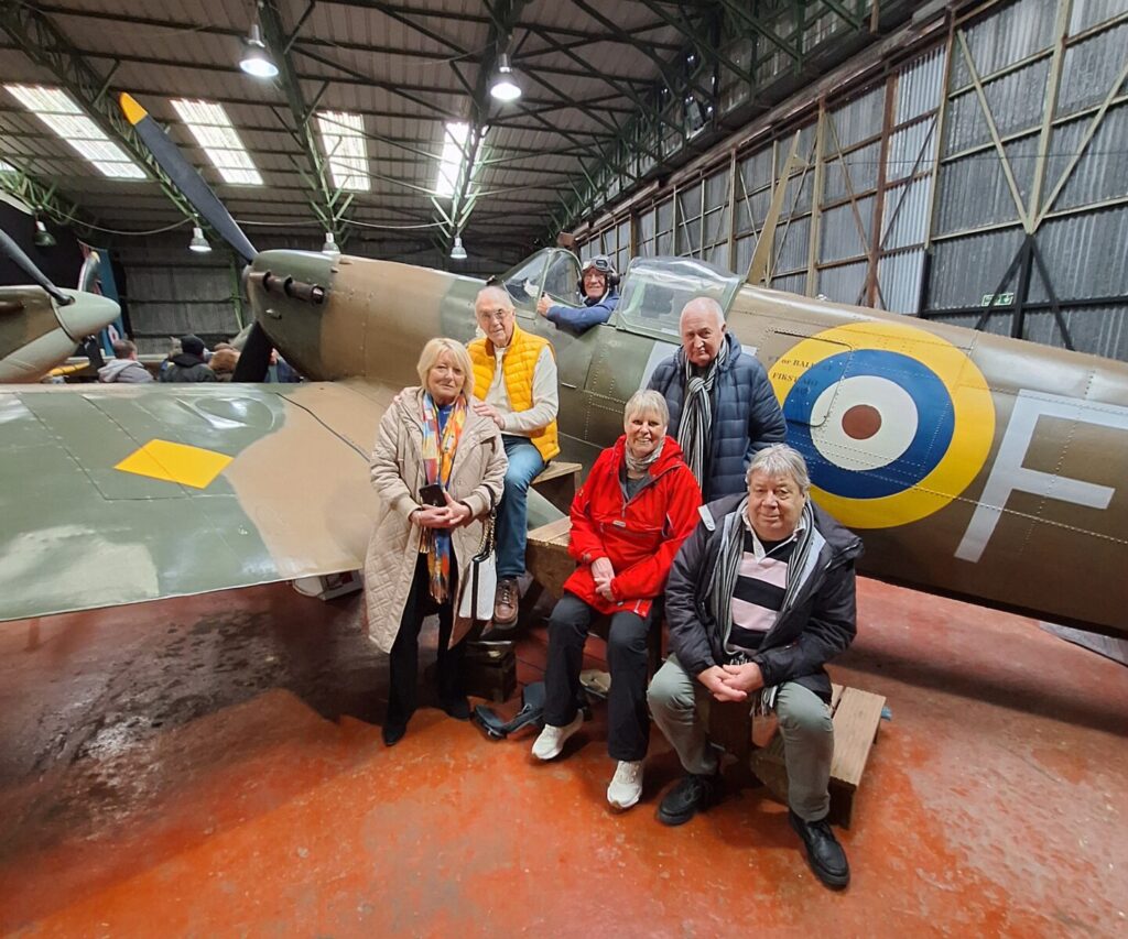 Geoff in the cockpit of a Spitfire together with his supporting Meols U3A ground crew. Geoff doing a thumbs up from the cockpit.