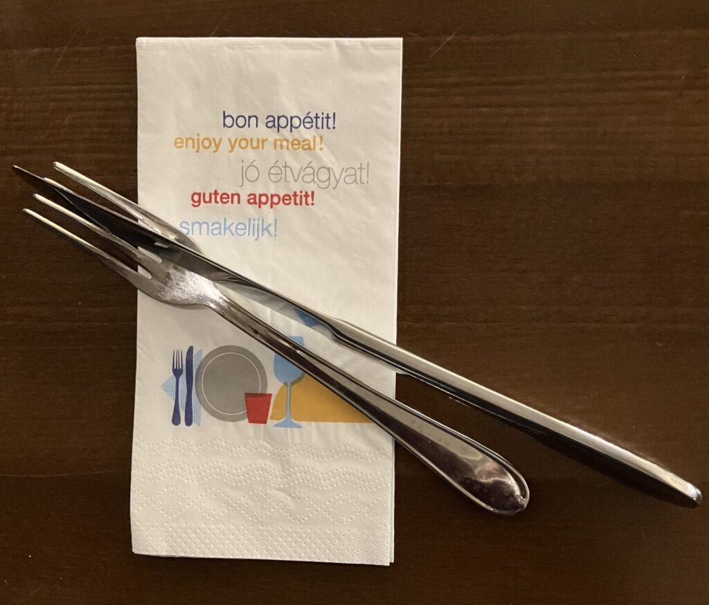 Serviette with enjoy your meal in five languages to represent cuisine from around the world. Cutlery laid on top